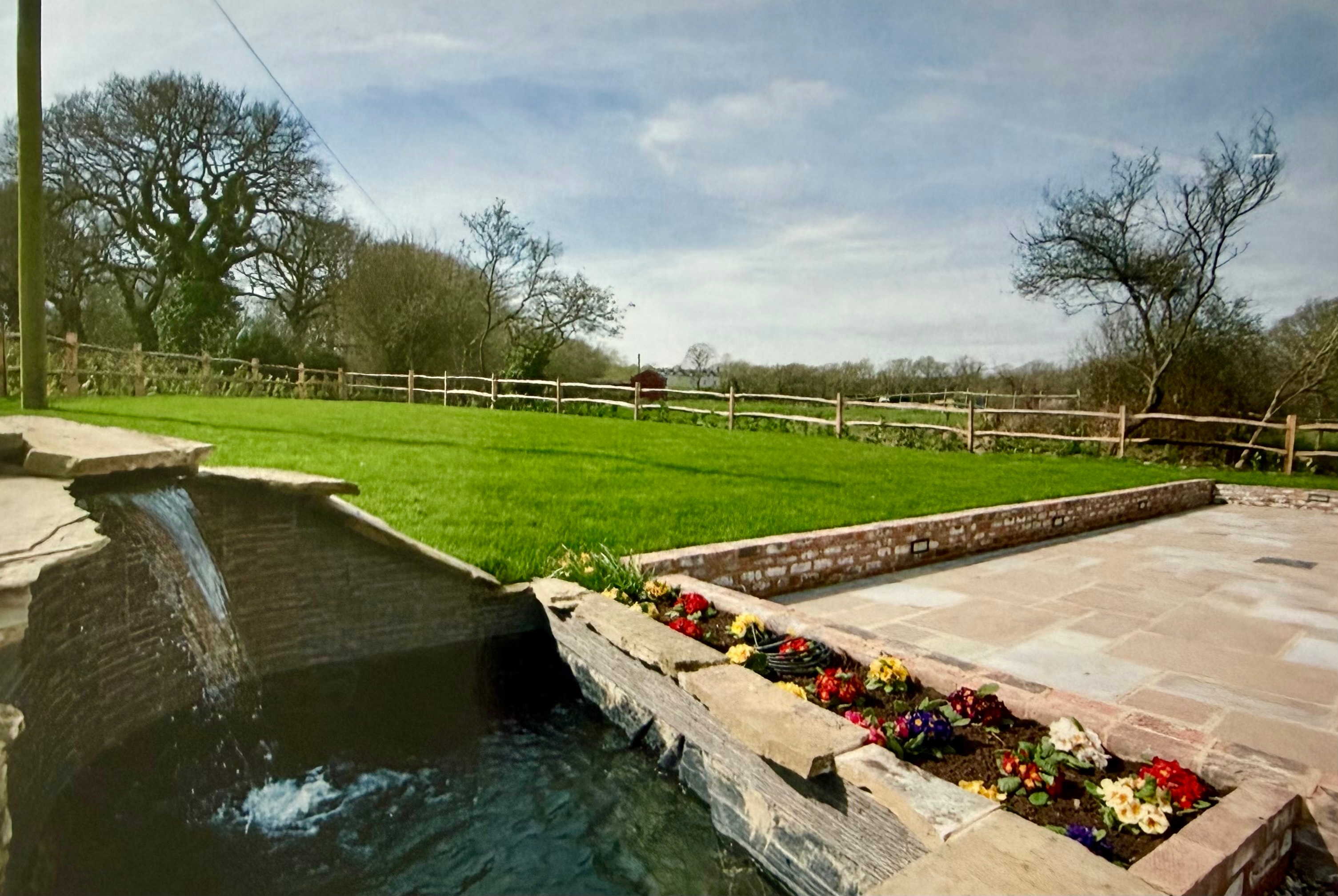 Patio with Steps & Borders in Polegate : Natural stone patio with water feature and flower beds